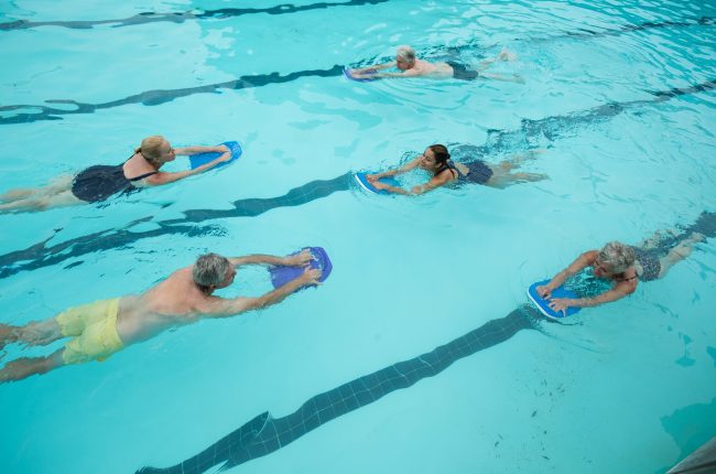 Trainer with senior swimmers swimming in pool