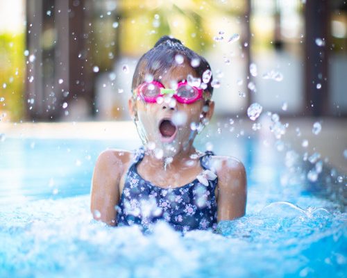Young girl jumping in the pool